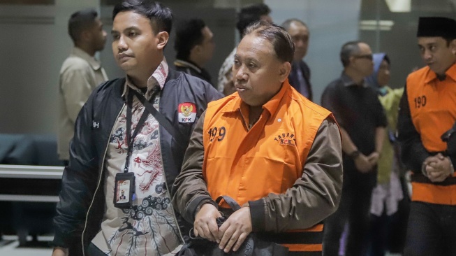 Rektor Universitas Jenderal Soedirman (Unsoed)  bersama tersangka lainnya berjalan menuju mobil tahanan usai menjalani pemeriksaan pasca terjaring operasi tangkap tangan (OTT) di Gedung KPK, Jakarta, Sabtu (22/8/2026) dini hari. [Suara.com/Alfian Winanto]