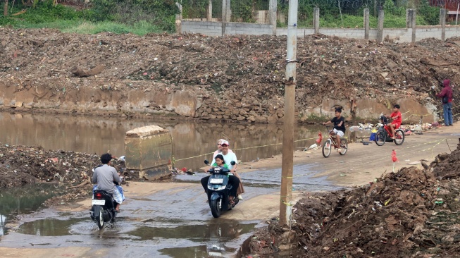 Pengendara melintasi akses jalan penghubung Kecamatan Cipayung dan Pasir Putih Sawangan yang sempat terendam selama empat tahun di Kampung Bulak Barat, Cipayung, Kota Depok, Jawa Barat, Jumat (21/8/2026). [ANTARA FOTO/Yulius Satria Wijaya/foc]
