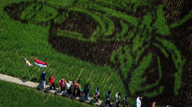 Foto udara warga melihat karya seni pari corek bergambar Sang Buddha karya seniman Sidik Gunawan di area persawahan Dusun Sidorejo, Bergas Lor, Kabupaten Semarang, Jawa Tengah, Selasa (25/8/2026). [ANTARA FOTO/Aprillio Akbar/kye]