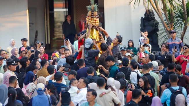 Sejumlah warga merayah gunungan berisi sayur-sayuran saat prosesi Grebeg Maulud di Taman Mini Indonesia Indah, Jakarta, Selasa (25/8/2026).  [Suara.com/Alfian Winanto]