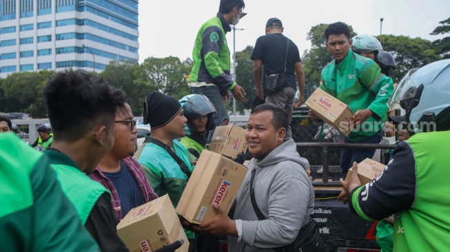 Pengemudi ojek online (ojol) membantu memindahkan logistik di depan Gedung DPR RI, Jakarta, Rabu (26/8/2026). [Suara.com/Alfian Winanto]
