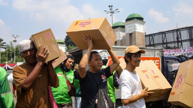 Pengemudi ojek online (ojol) membantu memindahkan logistik di depan Gedung DPR RI, Jakarta, Rabu (26/8/2026). [Suara.com/Alfian Winanto]
