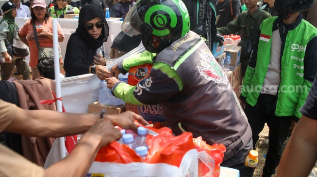 Pengemudi ojek online (ojol) membantu memindahkan logistik di depan Gedung DPR RI, Jakarta, Rabu (26/8/2026). [Suara.com/Alfian Winanto]
