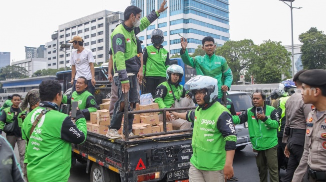 Pengemudi ojek online (ojol) membantu memindahkan logistik di depan Gedung DPR RI, Jakarta, Rabu (26/8/2026). [Suara.com/Alfian Winanto]
