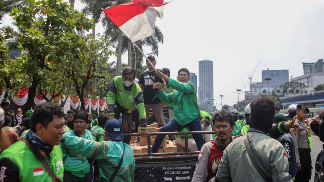 Pengemudi ojek online (ojol) membantu memindahkan logistik di depan Gedung DPR RI, Jakarta, Rabu (26/8/2026). [Suara.com/Alfian Winanto]
