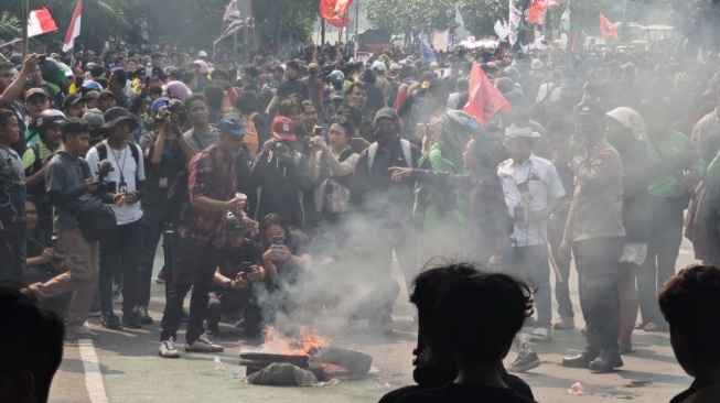 Massa aksi demo mahasiswa membakar ban setelah tertahan oleh barikade aparat kepolisian di kolong flyover Ladokgi, Senayan, Jakarta, Kamis (27/8/2026). [Suara.com/Adiyoga]