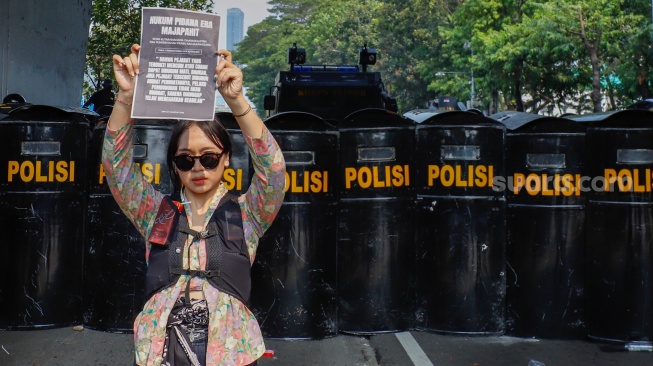 Salah seorang peserta demo menampilkan posternya saat menggelar aksi di depan Gedung DPR RI, Jakarta, Kamis (28/8/2026). [Suara.com/Alfian Winanto]