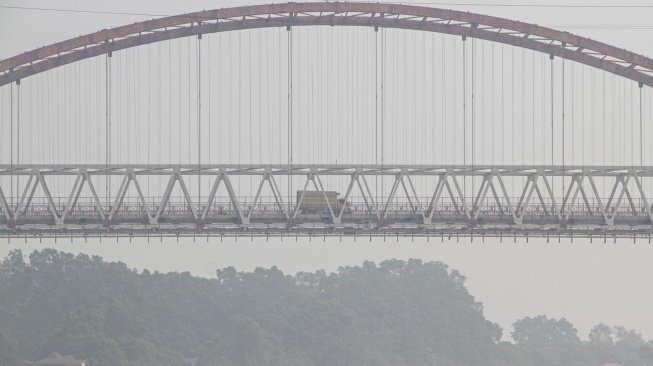 Kendaraan melintas di Jembatan Kahayan yang diselimuti asap dampak kebakaran hutan dan lahan di Palangka Raya, Kalimantan Tengah, Jumat (28/8/2026). [ANTARA FOTO/Auliya Rahman/nym]