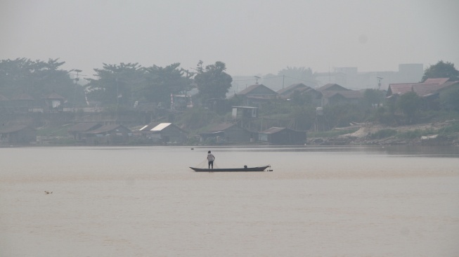 Seorang nelayan mencari ikan di Sungai Kahayan yang diselimuti asap dampak kebakaran hutan dan lahan di Palangka Raya, Kalimantan Tengah, Jumat (28/8/2026). [ANTARA FOTO/Auliya Rahman/nym]