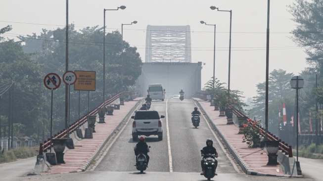 Pengendara melintas di Jembatan Kahayan yang diselimuti asap dampak kebakaran hutan dan lahan di Palangka Raya, Kalimantan Tengah, Jumat (28/8/2026). [ANTARA FOTO/Auliya Rahman/nym]