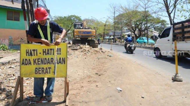 Pekerja memasang papan bicara pengerjaan jalan di Jalan Aroepala, Kabupaten Gowa. Proyek tersebut bagian dari Multi Years Project paket I yang hampir selesai dikerjakan [SuaraSulsel.id/Lorensia Clara]