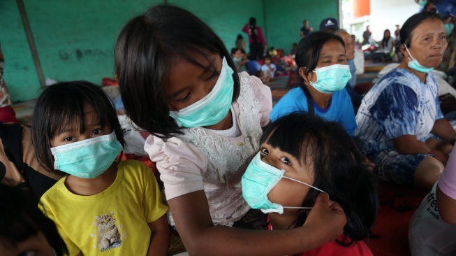 Seorang anak memasangkan masker ke temannya di posko pengungsian erupsi Gunung Sinabung di Desa Sukatepu, Kecamatan Naman Teran, Kabupaten Karo, Sumatera Utara, Selasa (1/9/2026). [ANTARA FOTO/Yudi Manar/tom]
 