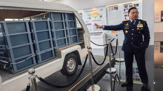 Kepala Biro Umum selaku Kepala Museum BNPT, Marsma TNI Asep Dicky Lukman Wijaya menunjukan mobil Mitsubishi putih bernomor polisi DK 1822 CW, salah satu artefak terkait peristiwa Bom Bali I pada 2002. [Suara.com/Adiyoga]