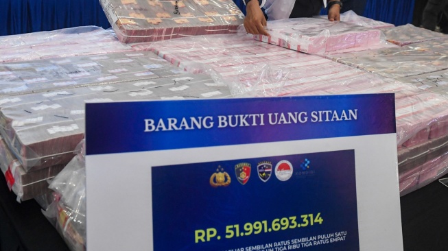 Petugas Direktorat Tindak Pidana Siber (Dittipidsiber) Polri menata barang bukti berupa pecahan uang 100 ribu rupiah saat pengungkapan kasus kejahatan siber di Gedung Awaloedin Djamin Bareskrim Polri, Jakarta, Kamis (3/9/2026). [ANTARA FOTO/Muhammad Adimaja/agr]