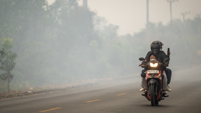 Pengendara sepeda motor melintas di Jalan Gubernur Syarkawi yang tertutup kabut asap akibat kebakaran hutan dan lahan (karhutla) di Kabupaten Banjar, Kalimantan Selatan, Rabu (2/9/2026). [ANTARA FOTO/Bayu Pratama S/nym]
