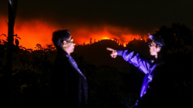 Warga melihat kebakaran di Gunung Merapi Ungup-ungup terlihat dari Gantasan, Banyuwangi, Jawa Timur, Jumat (4/9/2026). [ANTARA FOTO/Budi Candra Setya/sgd]