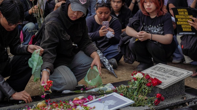 Dua mahasiswa menabur bunga dalam aksi simbolik mengenang 22 tahun kematian Munir Said Thalib di TPU Sisir, Kota Batu, Jawa Timur, Senin (7/9/2026). [ANTARA FOTO/Irfan Sumanjaya/nym]