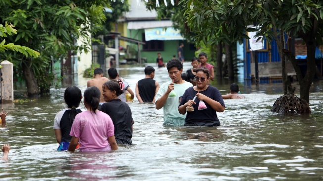 Sejumlah warga berjalan menerobos banjir di Martubung, Kecamatan Medan Labuhan, Kota Medan, Sumatera Utara, Kamis (10/9/2026). [ANTARA FOTO/Yudi Manar/wsj]