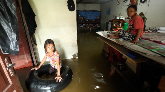 Ibu dan anak berada di dalam rumahnya yang terendam banjir di Martubung, Kecamatan Medan Labuhan, Kota Medan, Sumatera Utara, Kamis (10/9/2026). [ANTARA FOTO/Yudi Manar/wsj]