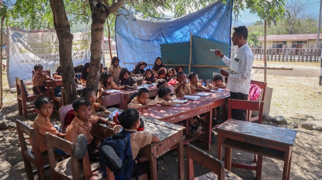 Guru menyampaikan pelajaran kepada siswa di bawah pohon karena gedung kelas mereka rusak di SDN Jarak, Desa Golo Mori, Kecamatan Komodo, Manggarai Barat, NTT, Rabu (9/9/2026). [ANTARA FOTO/Gecio Viana/app/nym]