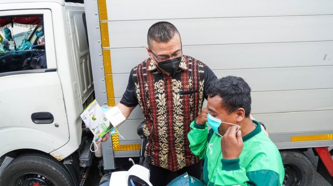 Anggota Komisi C DPRD DKI Jakarta Hardiyanto Kenneth membagikan masker gratis kepada masyarakat di Jalan Latumenten, Jakarta Barat. [Suara.com/dok]