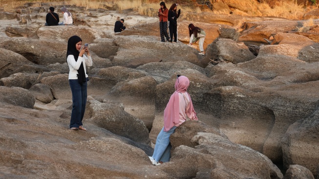 Warga berfoto di area aliran Sungai Jeneberang yang mengering di Kabupaten Gowa, Sulawesi Selatan, Minggu (13/9/2026). [ANTARA FOTO/Arnas Padda/hma]
