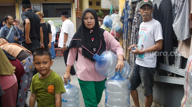 Warga membawa wadah kosong untuk diisi air bersih di Lenteng Agung, Jakarta, Jumat (18/9/2026). [Suara.com/Alfian Winanto]