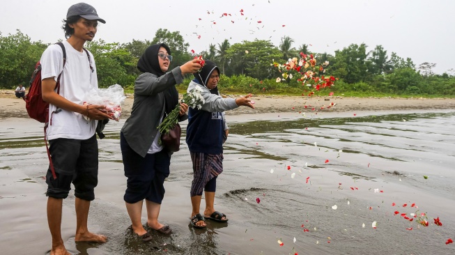 Istri dan ibu jurnalis ANTARA yang hilang kontak, M Bagus Khoirunas, Desi Purnama Sari (kiri), Tini (tengah) dan Korlip Antara Foto Sigid Kurniawan (kiri) berdoa usai melakukan tabur bunga di bibir Pantai Kampung Pagedongan, Carita, Pandeglang, Banten, Jumat (18/9/2026). [ANTARA FOTO/Angga Budhiyanto/agr]