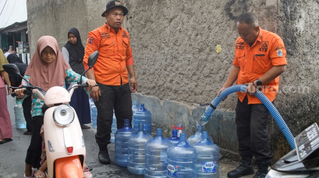Personel BPBD Jakarta Selatan mengisi air ke dalam wadah milik warga yang terdampak kekeringan di Lenteng Agung, Jakarta, Jumat (18/9/2026). [Suara.com/Alfian Winanto]