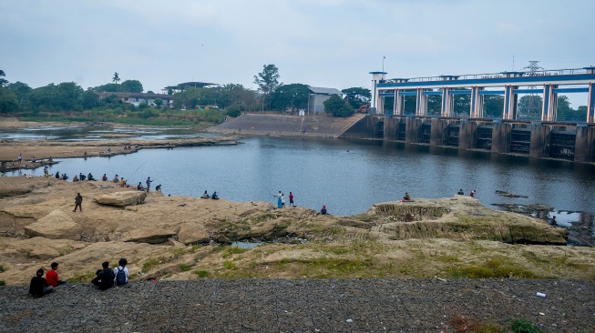 Warga memancing ikan di Sungai Cisadane yang airnya surut di Kota Tangerang, Banten, Jumat (18/9/2026). [ANTARA FOTO/Putra M. Akbar/wpa]