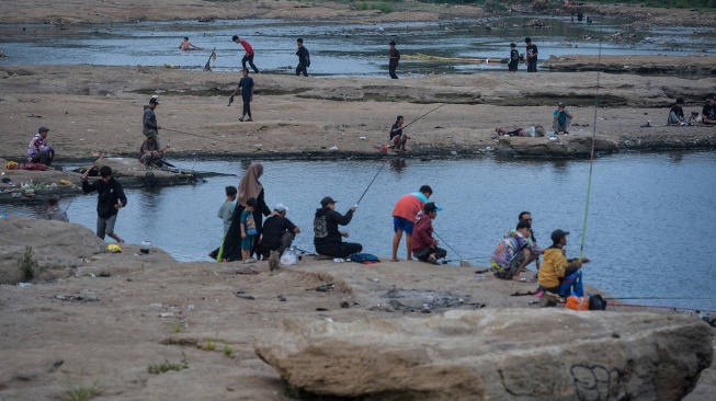 Warga memancing ikan di Sungai Cisadane yang airnya surut di Kota Tangerang, Banten, Jumat (18/9/2026). [ANTARA FOTO/Putra M. Akbar/wpa]