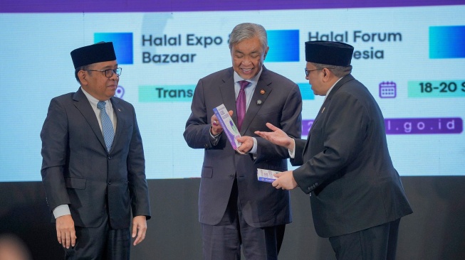 Menko PMK Pratikno (kiri), menyaksikan Kepala Badan Penyelenggara Jaminan Produk Halal (BPJPH) Ahmad Haikal Hasan (kanan) memberikan buku kepada  Wakil Perdana Menteri Malaysia Ahmad Zahid Hamidi, saat menghadiri pembukaan Halal 20 (H20) Summit ke-5 di Jakarta, Jumat (18/9/2026). [handout]