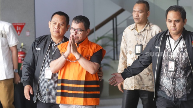 Bupati Bolaang Mongondow Utara, Sirajudin Lasena (tengah) mengenakan rompi tahanan berjalan menuju mobil tahanan usai menjalani pemeriksaan di Gedung Merah Putih KPK, Jakarta, Selasa (22/9/2026). [Suara.com/Alfian Winanto]