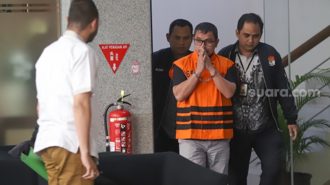 Bupati Bolaang Mongondow Utara, Sirajudin Lasena (tengah) mengenakan rompi tahanan berjalan menuju mobil tahanan usai menjalani pemeriksaan di Gedung Merah Putih KPK, Jakarta, Selasa (22/9/2026). [Suara.com/Alfian Winanto]