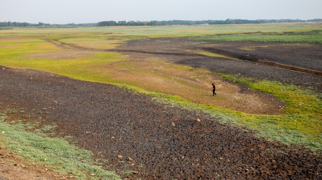 Warga berlajan di dasar Waduk Cipancuh yang mengering di Haurgeulis, Indramayu, Jawa Barat, Minggu (27/9/2026). [ANTARA FOTO/Dedi Suwidiantoro/sgd]
