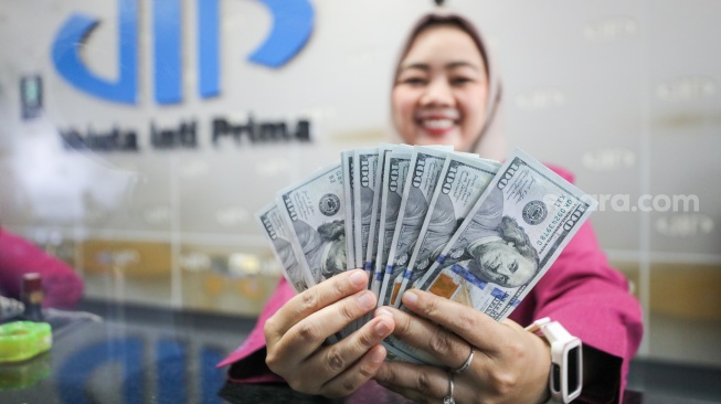 Petugas salah satu tempat penukaran mata uang asing menunjukkan mata uang dollar AS di Jakarta, Selasa (29/9/2026). [Suara.com/Alfian Winanto]