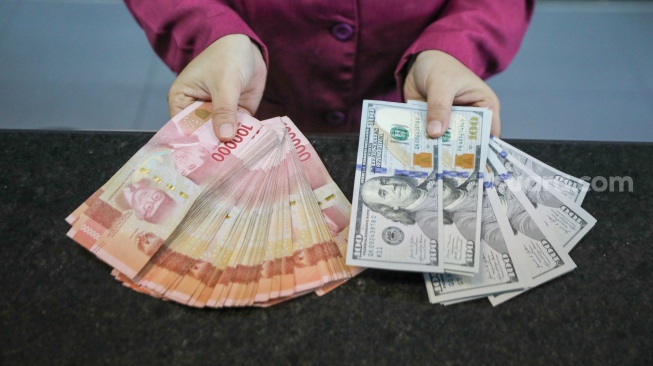 Petugas salah satu tempat penukaran mata uang asing menunjukkan uang rupiah dan dollar AS di Jakarta, Selasa (29/9/2026). [Suara.com/Alfian Winanto]