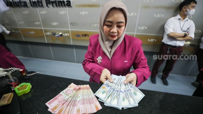 Petugas salah satu tempat penukaran mata uang asing menunjukkan uang rupiah dan dollar AS di Jakarta, Selasa (29/9/2026). [Suara.com/Alfian Winanto]