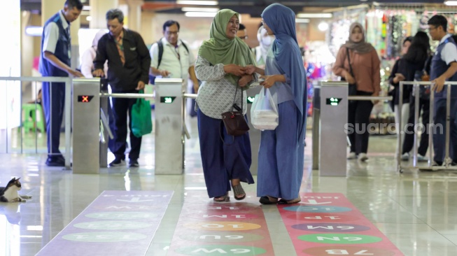 Pengguna transportasi umum berjalan mengikuti penunjuk arah (wayfinding) di area Terminal Blok M, Jakarta Selatan, Rabu (30/9/2026). [Suara.com/Alfian Winanto]