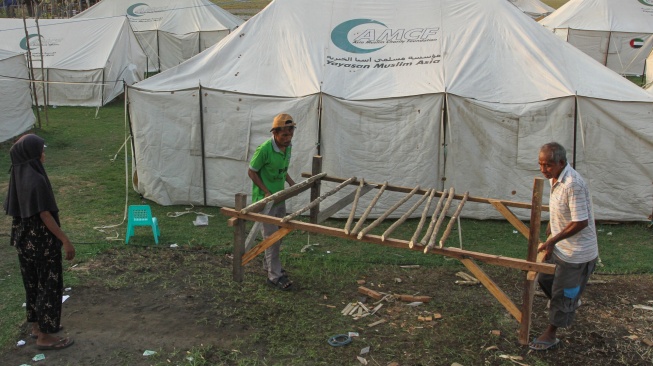 Sejumlah warga mengangkat alas tempat tidur untuk diletakkan di dalam tenda pengungsian, di Tendakinde, Kabupaten Nagekeo, Nusa Tenggara Timur, Selasa (29/9/2026). [ANTARA FOTO/Mega Tokan/app/rwa]
