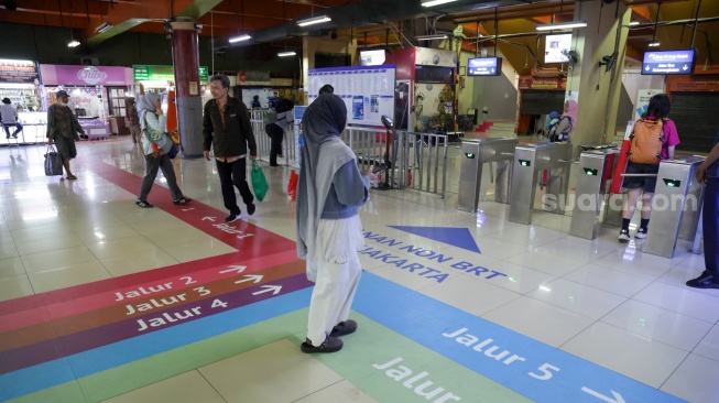 Pengguna transportasi umum berjalan mengikuti penunjuk arah (wayfinding) di area Terminal Blok M, Jakarta Selatan, Rabu (30/9/2026). [Suara.com/Alfian Winanto]
