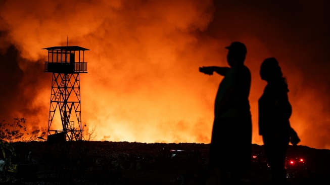 Sejumlah warga menyaksikan api yang membakar tumpukan sampah di Tempat Pembuangan Akhir (TPA) Jatibarang Zona 1, Semarang, Jawa Tengah, Rabu (30/9/2026). [ANTARA FOTO/Aprillio Akbar/YU]