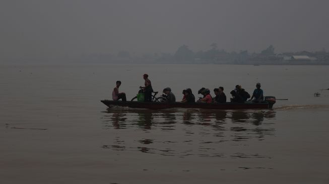 Sebuah perahu motor mengangkut penumpang melintasi Sungai Kapuas yang diselimuti kabut asap di Pontianak, Kalimantan Barat, Kamis (8/10/2026). [ANTARA FOTO/Jessica Wuysang/ky]