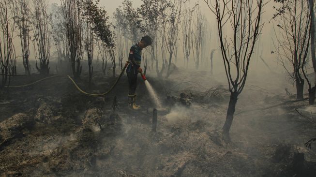 Petugas berupaya memadamkan kebakaran lahan yang mendekati kawasan permukiman warga di Kecamatan Jekan Raya, Palangka Raya, Kalimantan Tengah, Jumat (9/10/2026). [ANTARA FOTO/Auliya Rahman/wsj]