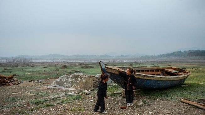 Dua orang anak bermain diantara perahu yang karam di tepian Waduk Jatigede yang surut di Desa Cipaku, Kecamatan Darmaraja, Kabupaten Sumedang, Jawa Barat, Minggu (11/10/2026). [ANTARA FOTO/Raisan Al Farisi/bar]