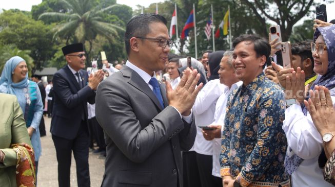 Menteri Luar Negeri Arrmanatha Nasir (kanan) bersama Pejabat lama Menteri Luar Negeri Sugiono (kiri) didampingi istri menyapa pegawai Kementerian Luar Negeri dalam acara pisah sambut pejabat baru dan lama di Gedung Pancasila, Kementerian Luar Negeri, Jakarta, Senin (12/10/2026). [Suara.com/Alfian Winanto]