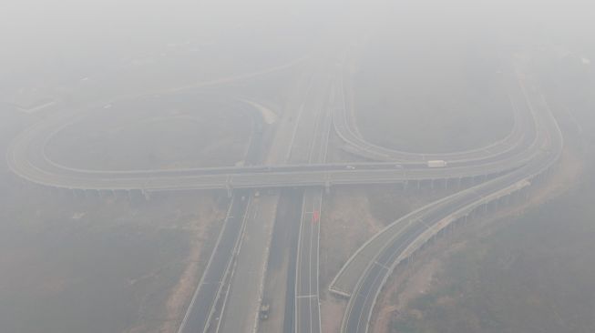 Sejumlah kendaraan melintas di simpang susun Jalan Tol Trans Sumatera (JTTS) ruas Palembang-Lampung yang tertutup kabut asap di Desa Ibul Besar III, Pemulutan, Ogan Ilir (OI), Sumatera Selatan, Selasa (13/10/2026). [ANTARA FOTO/Nova Wahyudi/tom]