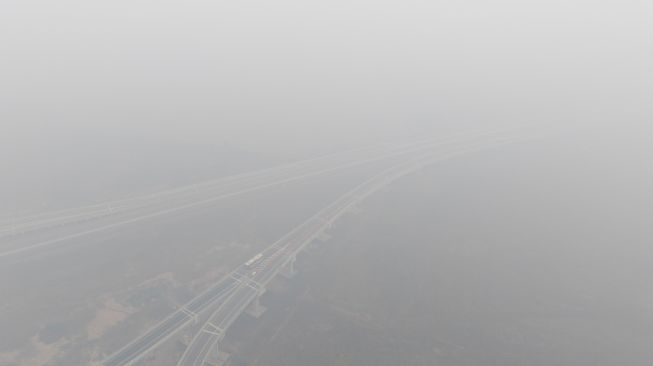 Sejumlah kendaraan melintas di simpang susun Jalan Tol Trans Sumatera (JTTS) ruas Palembang-Lampung yang tertutup kabut asap di Desa Ibul Besar III, Pemulutan, Ogan Ilir (OI), Sumatera Selatan, Selasa (13/10/2026). [ANTARA FOTO/Nova Wahyudi/tom]