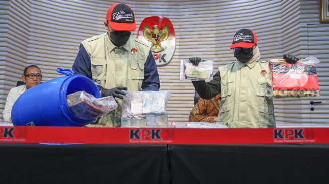 Petugas menunjukan barang bukti dari dalam tong dari kasus OTT Bupati Klaten Hamenang Wajar Ismoyo saat konferensi pers di Gedung Merah Putih KPK, Jakarta, Jumat (16/10/2026). [Suara.com/Alfian Winanto]
