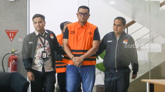 Bupati Klaten Hamenang Wajar Ismoyo (tengah) berjalan menggunakan rompi tahanan usai menjalani pemeriksaan di Gedung Merah Putih KPK, Jakarta, Jumat (16/10/2026). [Suara.com/Alfian Winanto]
